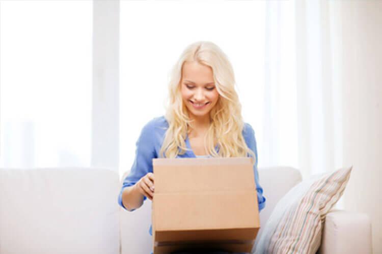 Woman sitting on couch opening box